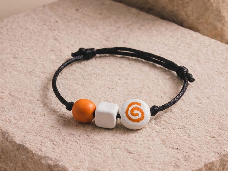 The bracelet for this brief: a terracotta bead, a bone cube and a bone bead painted with a spiral.