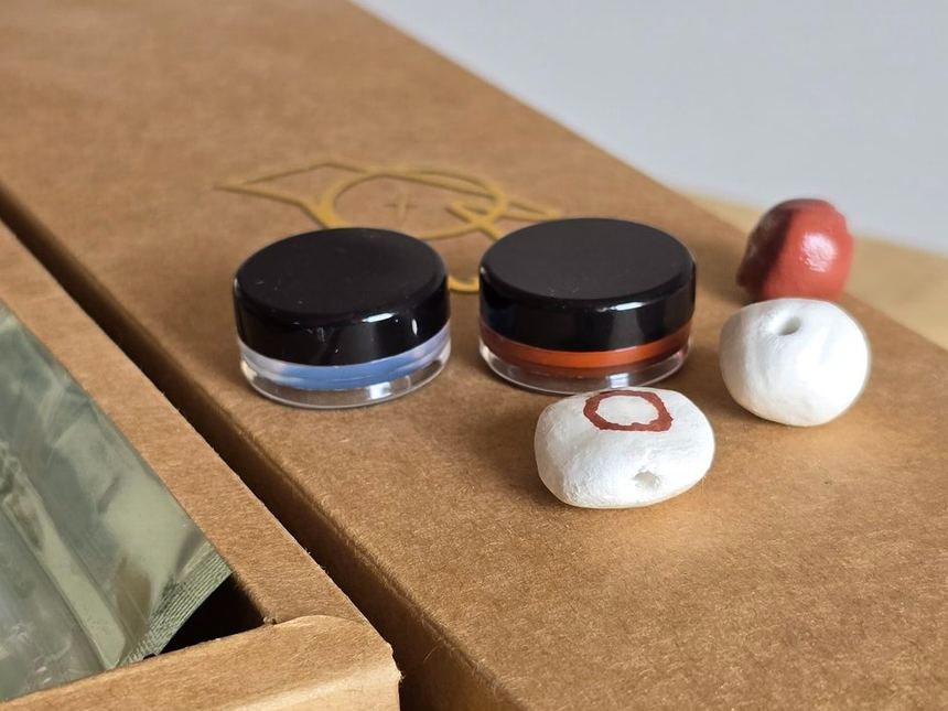 Paint pots and hand-shaped clay beads on the kit's kraft tray.